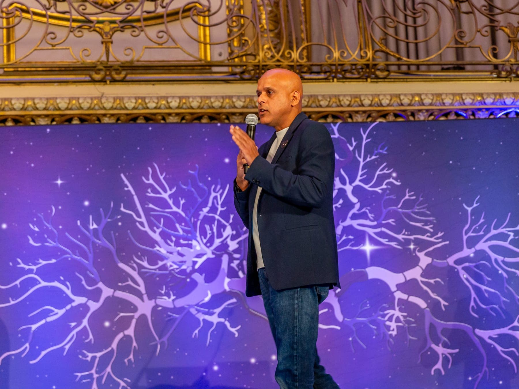Manuj Aggarwal speaking on stage with a microphone
